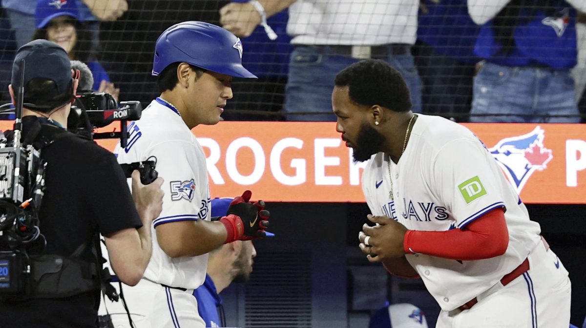 アスレチックス戦の４回、メジャー初本塁打を放ちゲレロ（中央）に迎えられるブルージェイズ・岡本（左）＝トロント（共同）